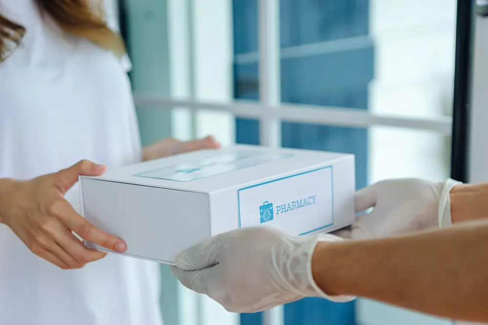 Pharmacy courier handing off a packaged delivery box